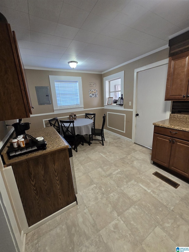 kitchen with dark brown cabinetry, ornamental molding, and light stone counters