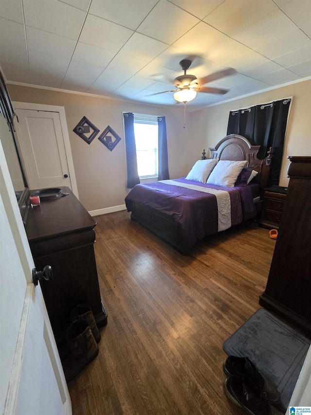 bedroom with crown molding, dark wood-type flooring, and ceiling fan