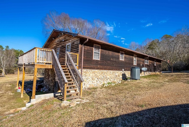 view of side of home featuring cooling unit, a wooden deck, and a yard