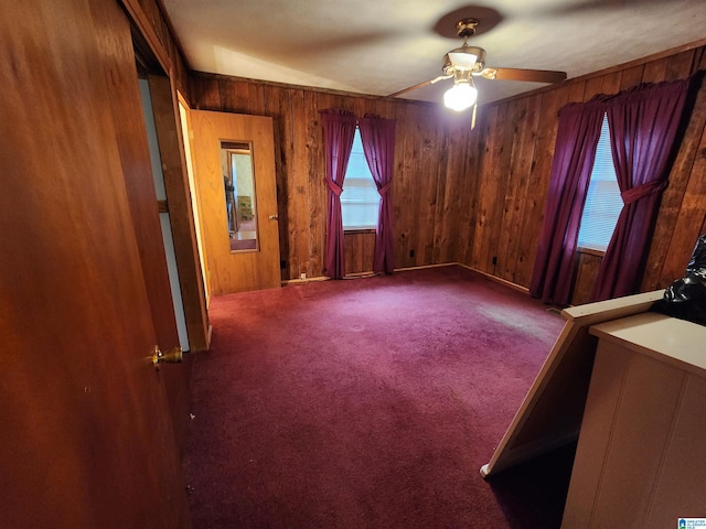 empty room featuring ceiling fan, wooden walls, and carpet flooring