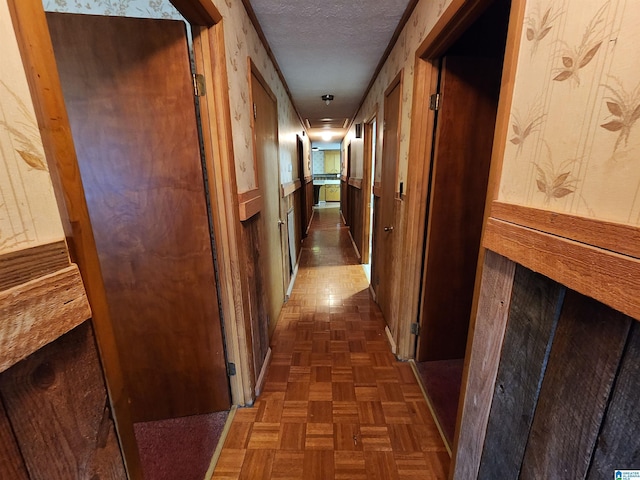 hallway featuring a textured ceiling and dark parquet floors