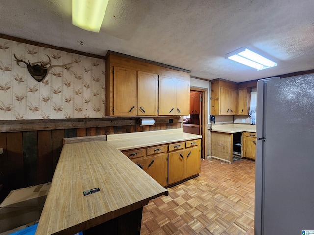 kitchen featuring white fridge, wooden counters, light parquet flooring, a textured ceiling, and crown molding