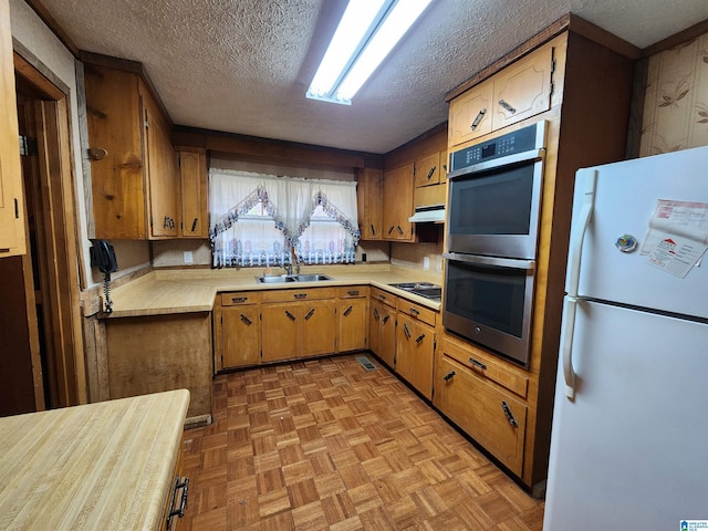 kitchen with white refrigerator, sink, black electric cooktop, a textured ceiling, and double oven