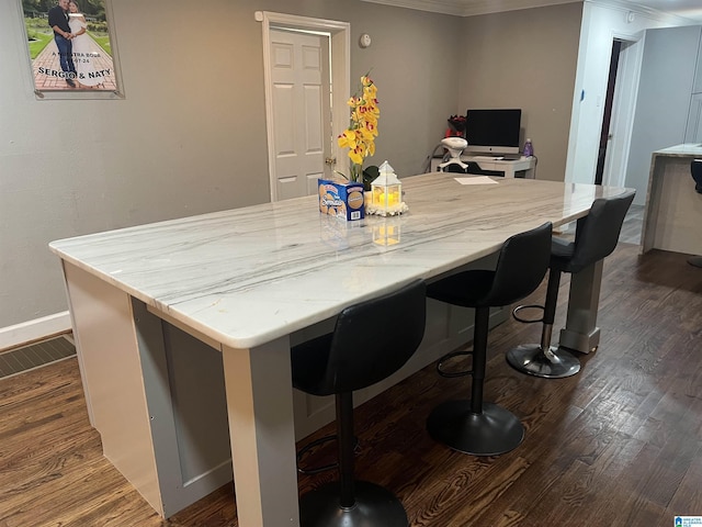 interior space with crown molding, dark wood-type flooring, a breakfast bar, and a center island