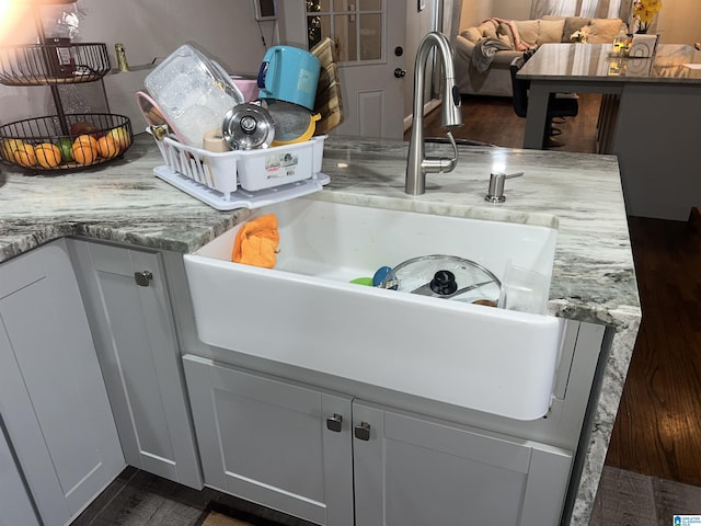 room details featuring sink, dark wood-type flooring, white cabinets, and light stone counters