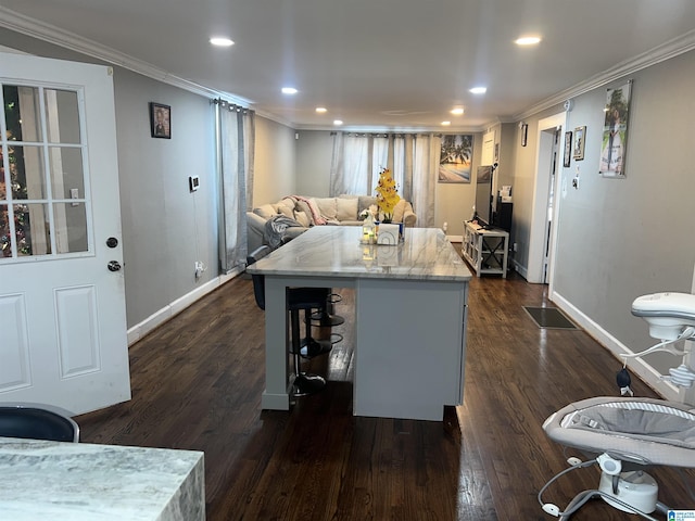 kitchen with crown molding, dark wood-type flooring, light stone countertops, and a kitchen island