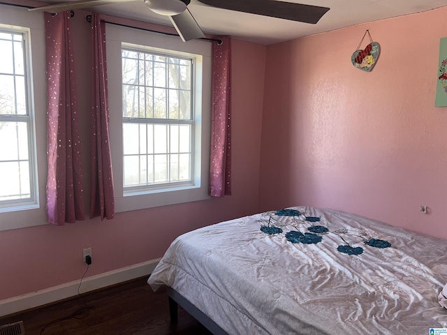 bedroom featuring multiple windows, dark hardwood / wood-style flooring, and ceiling fan