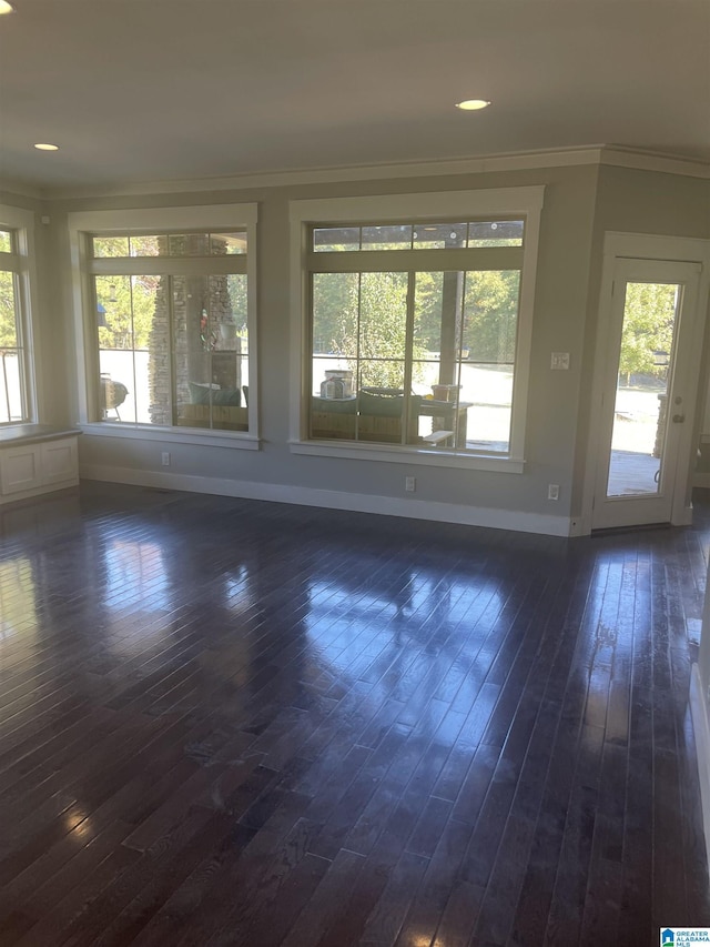 unfurnished room with crown molding, plenty of natural light, and dark hardwood / wood-style floors