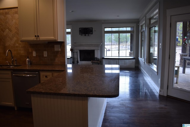 kitchen with a kitchen island, sink, dark stone countertops, dishwashing machine, and decorative backsplash