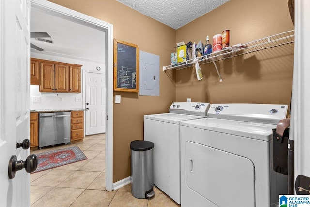 washroom featuring a textured ceiling, light tile patterned floors, electric panel, and washer and clothes dryer