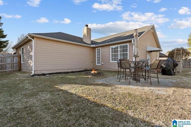 back of property with a lawn, a patio area, and a fire pit