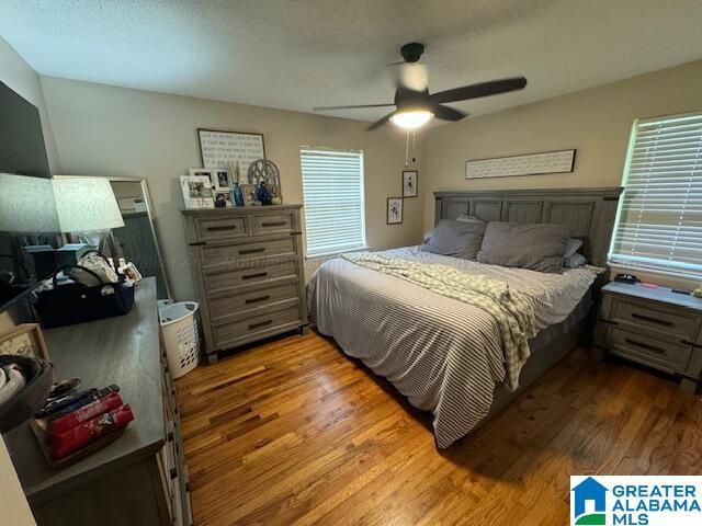 bedroom featuring hardwood / wood-style flooring, ceiling fan, and a textured ceiling