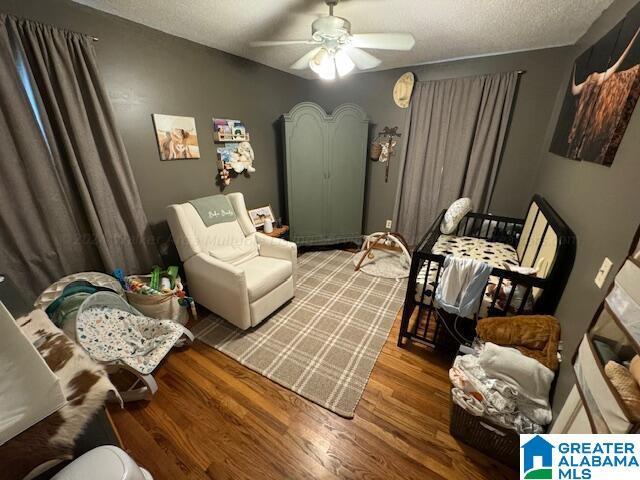 sitting room with hardwood / wood-style flooring, ceiling fan, and a textured ceiling