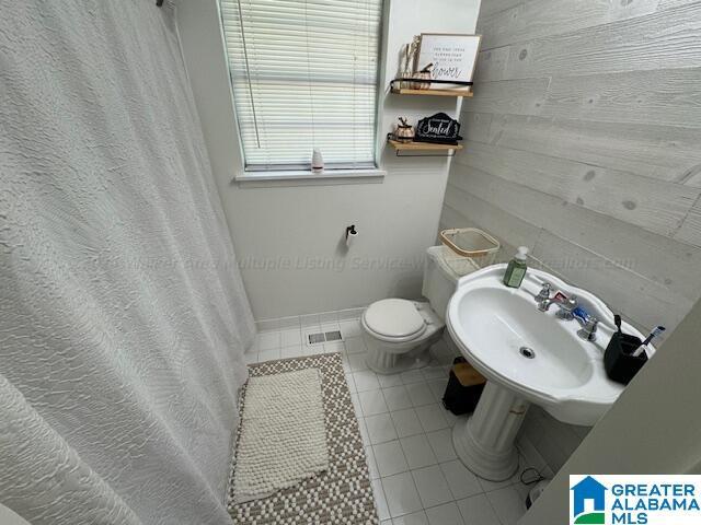 bathroom featuring tile patterned flooring, sink, curtained shower, and toilet