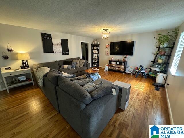 living room with hardwood / wood-style flooring, a chandelier, and a textured ceiling