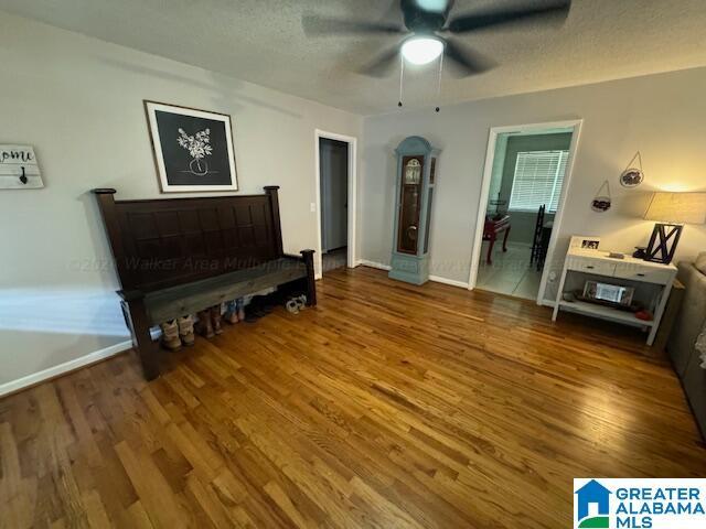 living room featuring hardwood / wood-style flooring, ceiling fan, and a textured ceiling