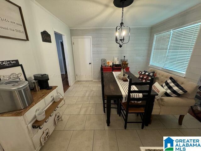 tiled dining space with an inviting chandelier and ornamental molding