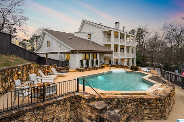 exterior space featuring a fenced in pool, a balcony, and a patio area