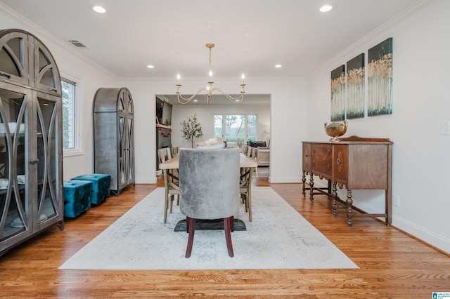 dining area with a notable chandelier, ornamental molding, and light wood-type flooring