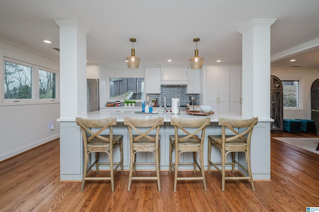 kitchen with white cabinetry, pendant lighting, crown molding, and ornate columns