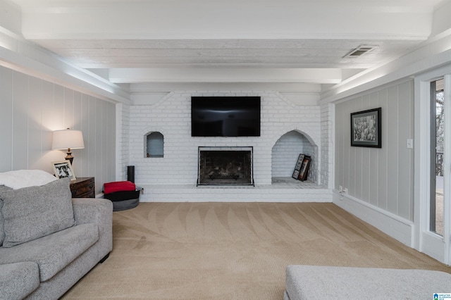 living room with a brick fireplace, carpet, and beam ceiling