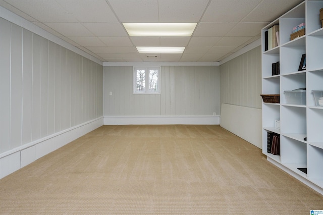 basement with a paneled ceiling and light carpet