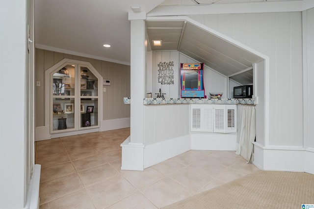 bar with light stone counters, lofted ceiling, and light tile patterned floors