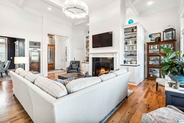 living room with light hardwood / wood-style flooring, a high ceiling, coffered ceiling, built in shelves, and beamed ceiling