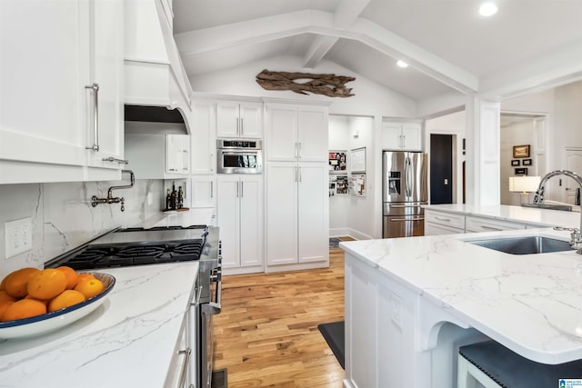 kitchen with sink, vaulted ceiling with beams, white cabinets, and appliances with stainless steel finishes