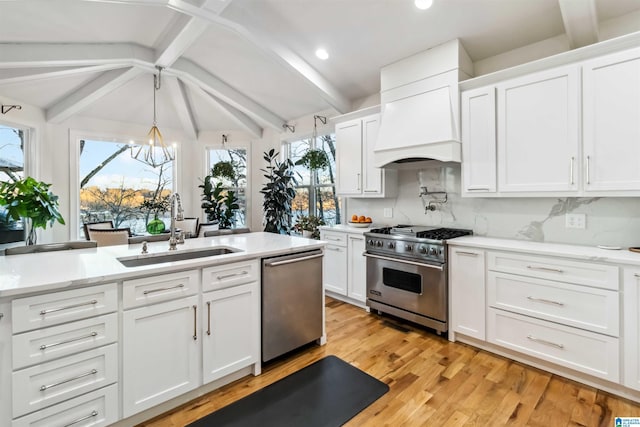 kitchen featuring premium range hood, sink, lofted ceiling with beams, appliances with stainless steel finishes, and white cabinets