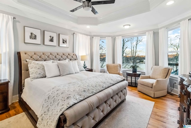 bedroom featuring ornamental molding, a raised ceiling, ceiling fan, and light wood-type flooring