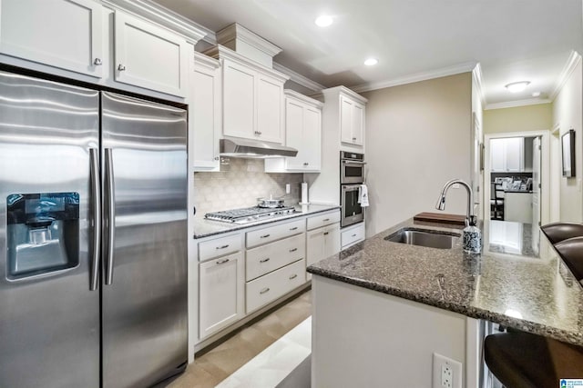 kitchen featuring a breakfast bar, sink, white cabinetry, appliances with stainless steel finishes, and decorative backsplash