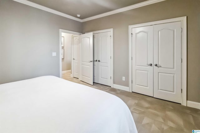 carpeted bedroom featuring crown molding and two closets