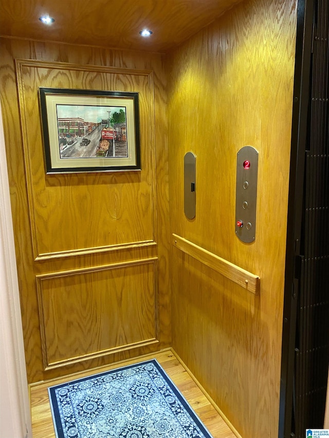 interior details with hardwood / wood-style flooring, elevator, and wood walls