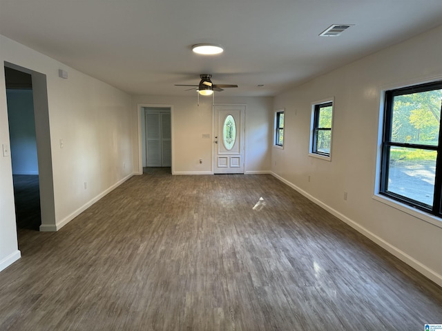 unfurnished living room featuring dark wood-type flooring and ceiling fan