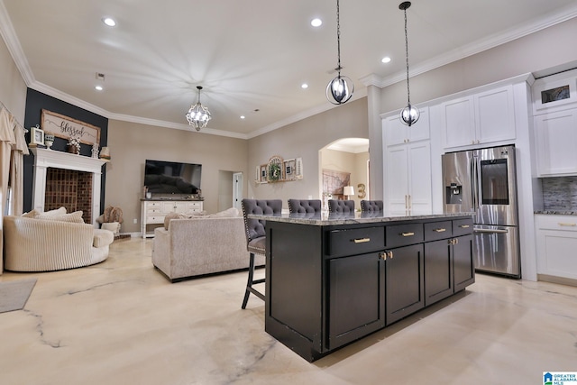 kitchen featuring white cabinetry, stainless steel fridge, a kitchen island, and pendant lighting