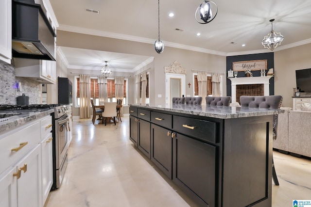 kitchen featuring gas stove, a chandelier, a center island, pendant lighting, and white cabinets