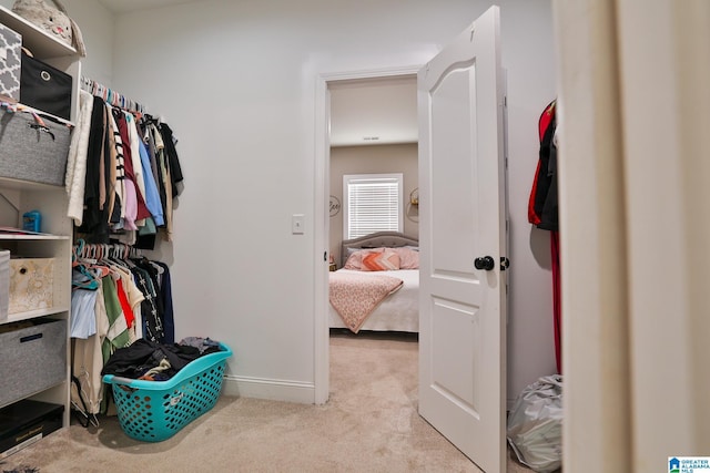 walk in closet with light colored carpet