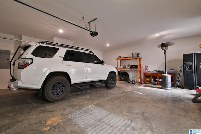 garage with a garage door opener, electric panel, and black refrigerator with ice dispenser