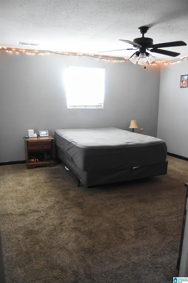 carpeted bedroom featuring ceiling fan and a textured ceiling