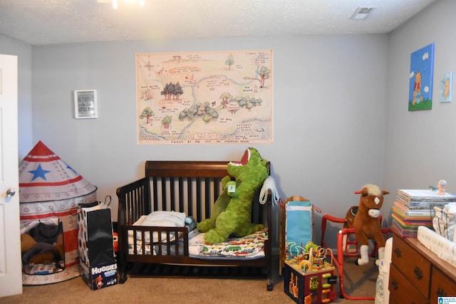 carpeted bedroom featuring a crib and a textured ceiling