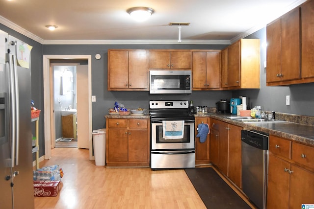 kitchen featuring ornamental molding, stainless steel appliances, sink, and light wood-type flooring