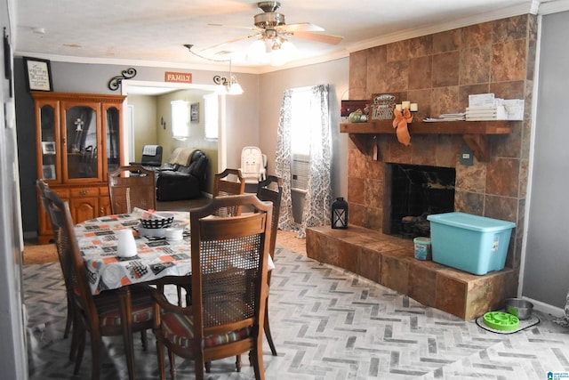 dining area with a tiled fireplace, ornamental molding, and ceiling fan