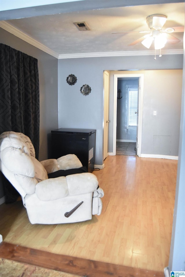 living room with crown molding, ceiling fan, and wood-type flooring