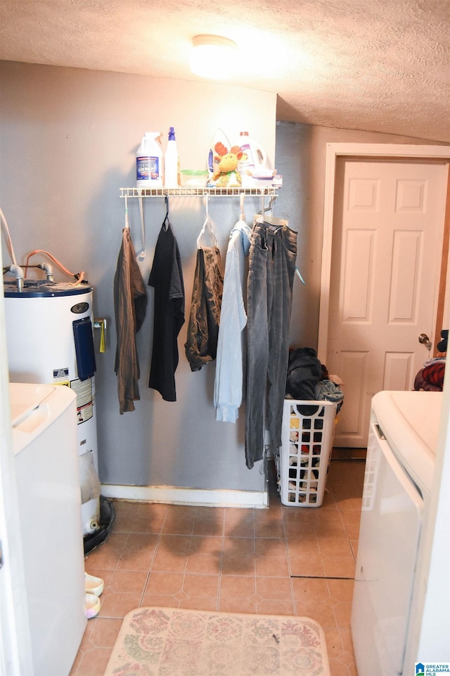 clothes washing area featuring water heater, tile patterned floors, independent washer and dryer, and a textured ceiling