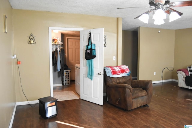 living area featuring ceiling fan, dark hardwood / wood-style floors, washer and clothes dryer, and a textured ceiling