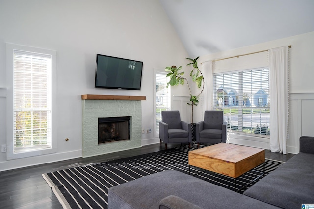 living room featuring a stone fireplace, dark wood-type flooring, and high vaulted ceiling