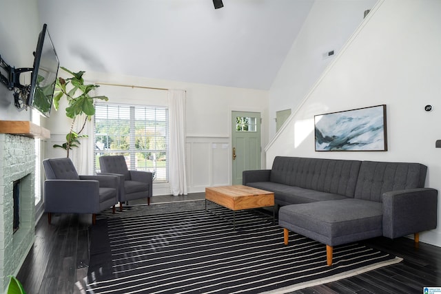 living room featuring dark hardwood / wood-style floors, high vaulted ceiling, and a brick fireplace