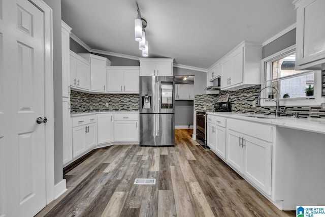 kitchen featuring ornamental molding, stainless steel appliances, hardwood / wood-style floors, and white cabinets