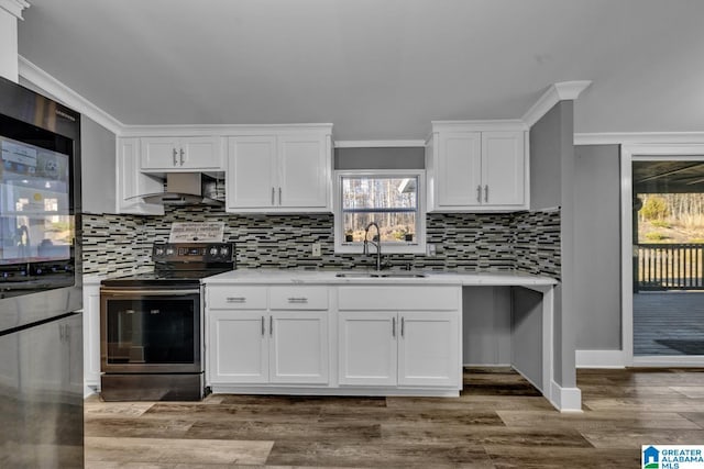 kitchen with hardwood / wood-style floors, white cabinetry, sink, stainless steel appliances, and wall chimney exhaust hood